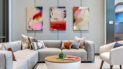 A modern lounge area with plush gray sofas, a round coffee table, and vibrant abstract wall art.