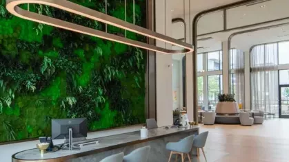 A reception area with a striking green living wall, elegant lighting, and a sleek modern desk with seating.