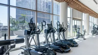 Well-equipped fitness center with cardio machines and large windows offering a cityscape view.