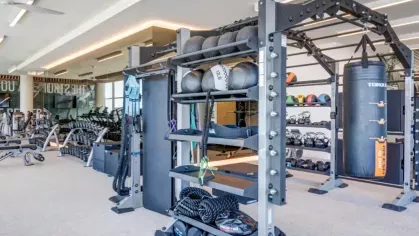 A well-equipped gym featuring weight training equipment, resistance bands, and a boxing bag.