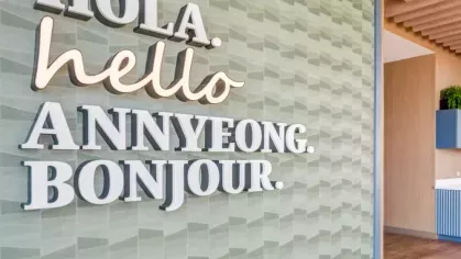 A welcoming wall with the words "Hola, hello, annyeong, bonjour" in a vibrant lobby.