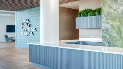 A modern lobby area with a reception desk, greenery, and stylish wood and stone accents.