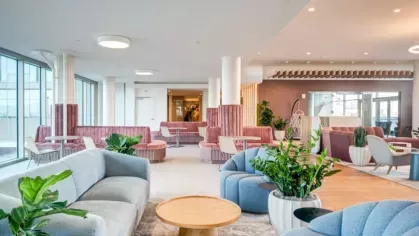 A colorful and airy lounge space with cozy seating, modern furniture, and floor-to-ceiling windows.