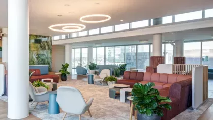 A communal lounge with contemporary seating, natural light, and vibrant greenery for a relaxing atmosphere.