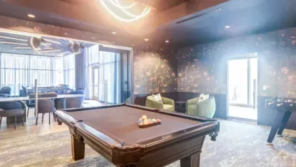 Stylish game room with a black pool table and floral wallpaper.