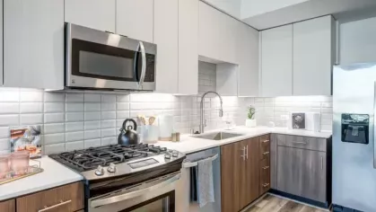 Contemporary kitchen with stainless steel appliances, white and wood-toned cabinets, and a subway tile backsplash.