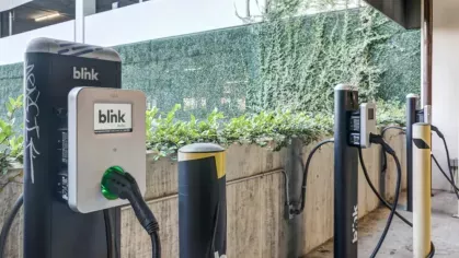 Electric vehicle charging stations with Blink chargers and greenery in a modern parking area.