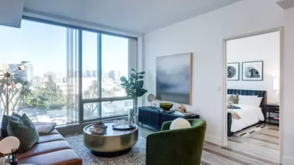Bright living room with floor-to-ceiling windows showcasing a city view and cozy seating area.