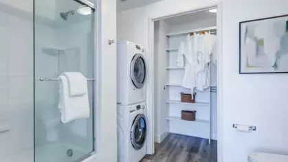 Bathroom with a glass-enclosed shower, stacked washer and dryer, and a walk-in closet.