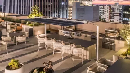 Stylish outdoor kitchen and dining area with multiple grills and contemporary seating.