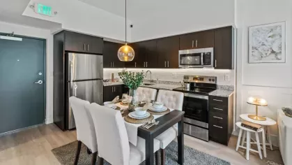 A well-appointed kitchen and dining space with granite countertops, a chic dining set, and a bright living room leading to a private patio.