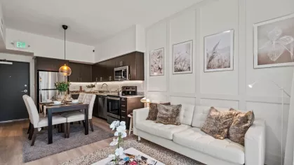 A sleek open-concept kitchen and living space with dark wood cabinetry, stainless steel appliances, and a stylish dining area with elegant pendant lighting.