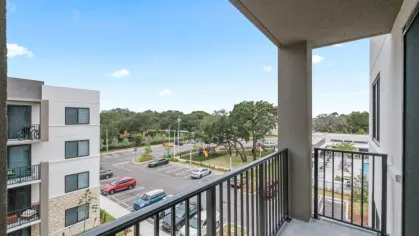 A spacious balcony at Oak Enclave Apartments offers stunning views of the landscaped community and nearby amenities.