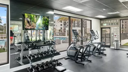 A bright, spacious workout facility at Oak Enclave Apartments equipped with ellipticals, treadmills, and a full rack of dumbbells for residents.