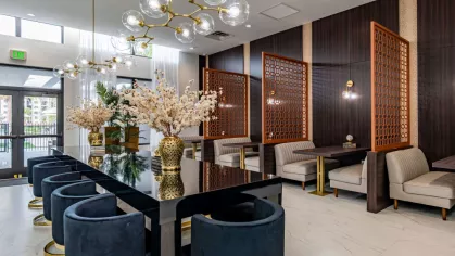 A chic clubhouse dining area with dark wood paneling, elegant chandeliers, and floral centerpieces for a refined gathering experience.