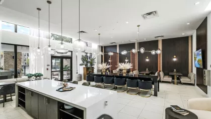 A sophisticated dining space in the clubhouse with plush seating, modern chandeliers, and expansive windows bringing in natural light.