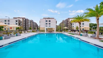 A stunning view of the resort-style pool at Oak Enclave, framed by contemporary apartment buildings and lush landscaping.