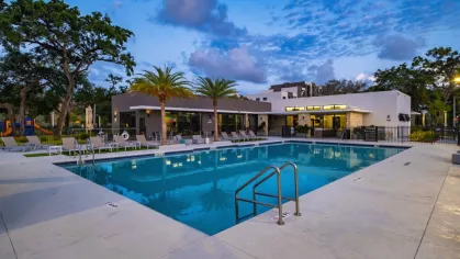 The pool at Oak Enclave illuminated at dusk, showcasing a peaceful and inviting atmosphere with warm lighting and stylish seating.