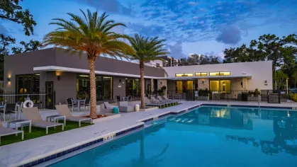 The evening glow highlights Oak Enclave’s upscale pool deck, featuring palm trees, modern lounge chairs, and a serene atmosphere.