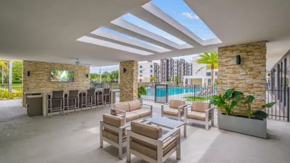 A beautifully designed outdoor bar and lounge with plush seating, overlooking the resort-style pool at Oak Enclave Luxury Apartments.