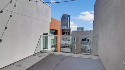 Private balcony at The Pacific Luxury Apartments with string lights and stunning city views.