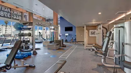 Expansive gym with state-of-the-art machines and a vibrant mural at The Pacific Luxury Apartments.