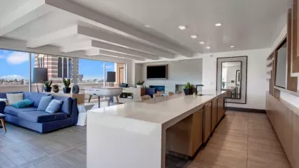 Spacious rooftop lounge with a modern kitchen, seating area, and panoramic city views.