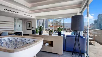 Foosball table and comfortable seating in the light-filled community room at The Pacific Luxury Apartments.