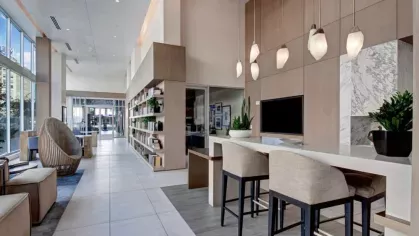 Elegant lobby with floor-to-ceiling windows, a stylish reading nook, and a built-in bookshelf at The Pacific Luxury Apartments.