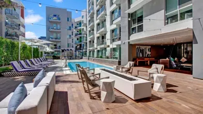 Outdoor social space with fire pit, string lights, and poolside seating at The Pacific Luxury Apartments.