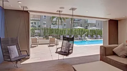 Cozy indoor-outdoor seating with swing chairs and pool views at The Pacific Luxury Apartments.