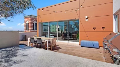"Spacious rooftop deck at The Pacific Luxury Apartments with built-in barbecue grills, dining areas, and sweeping views of the surrounding city architecture."