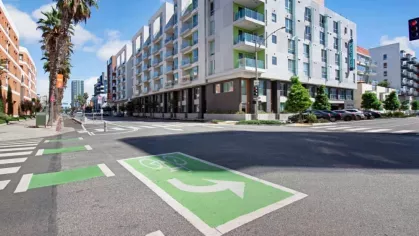 "Street view of The Pacific Luxury Apartments, showcasing the building's contemporary architecture, landscaped surroundings, and accessible bike lanes."