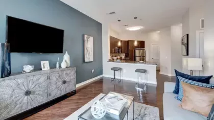 A modern living room with a blue accent wall, a large TV, and a stylish sofa adorned with decorative pillows.