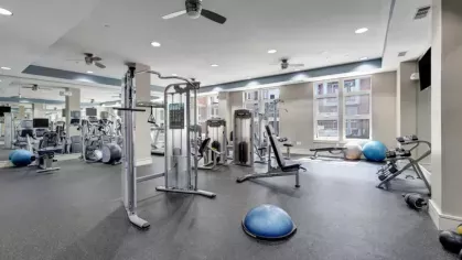 Spacious gym area featuring modern workout equipment and large windows.