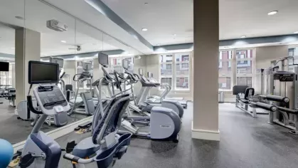 Cardio and strength training machines in a well-lit fitness room with mirrored walls.