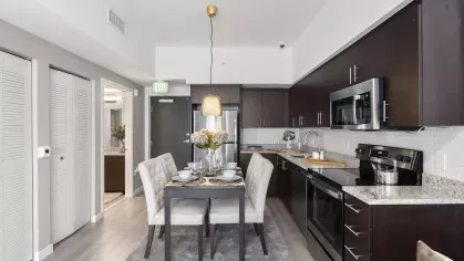 A sophisticated dining area next to a modern kitchen with a granite countertop, subway tile backsplash, and stainless steel appliances.