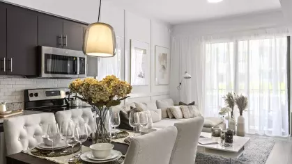 A sophisticated dining area next to a modern kitchen with a granite countertop, subway tile backsplash, and stainless steel appliances.