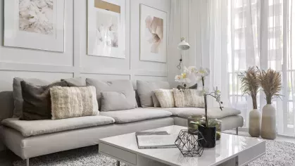 A tastefully decorated living room with soft furnishings, modern art, and a textured rug that adds a cozy touch.