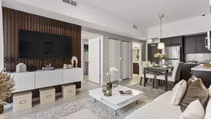 The open-plan living space at Pine Ridge Luxury Apartments, showcasing a contemporary dining area with upholstered chairs, a sleek kitchen with dark cabinetry, and a comfortable seating area.