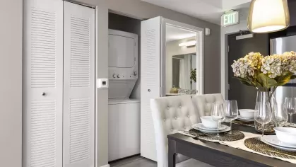 A built-in washer and dryer neatly concealed within a modern closet, located in a Pine Ridge Luxury Apartments unit.