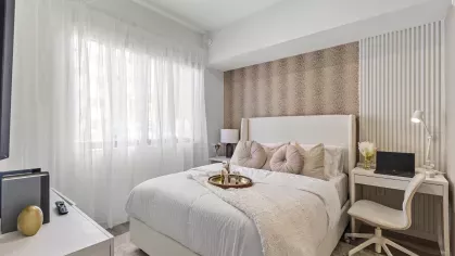 A modern bedroom featuring a mounted flat-screen TV, a sleek white console, and elegant decor at Pine Ridge Luxury Apartments.