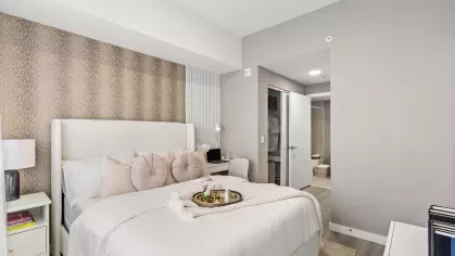A stylish bedroom with a cushioned headboard bed, soft throw pillows, and a functional desk setup, ideal for working from home at Pine Ridge Luxury Apartments.