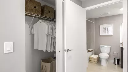 A spacious closet with white shelving and storage bins, adjacent to a modern bathroom with sleek fixtures and a neutral color palette at Pine Ridge Luxury Apartments.