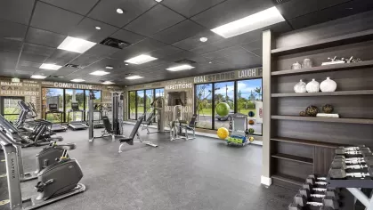 A spacious gym with state-of-the-art exercise equipment and motivational wall graphics, designed for an active lifestyle at Pine Ridge Luxury Apartments.