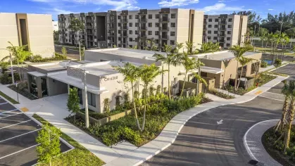 A wide shot of several apartment buildings with neatly arranged parking and lush landscaping, showcasing the community's welcoming design.