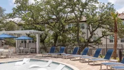 Luxurious poolside seating with in-water lounge chairs, shaded cabanas, and lush greenery, offering a resort-like escape within the community.