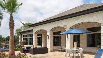 Resort-style poolside patio with lounge chairs, shaded dining tables, and vibrant landscaping, offering a relaxing retreat at Vista At Town Green Luxury Apartments.