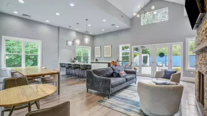 The Oak Enclave community room provides a versatile space with stylish seating, dining tables, and access to the pool, ideal for social gatherings and events.