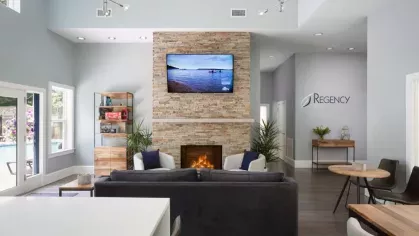 The stylish clubhouse at Oak Enclave Luxury Apartments features a contemporary design, a cozy stone fireplace, and elegant seating areas for residents to relax and socialize.